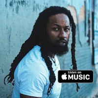 a man with dreadlocks standing in front of a wall